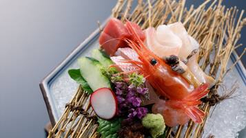 Una bandeja de sushi con diversos tipos de pescado y verduras sobre hielo.