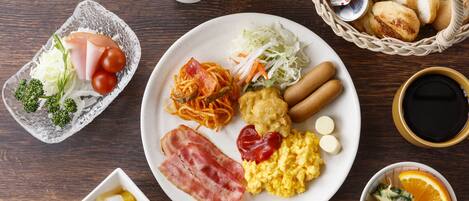 Un buffet de petit-déjeuner proposant divers plats, notamment des œufs, du bacon, des saucisses et des légumes.