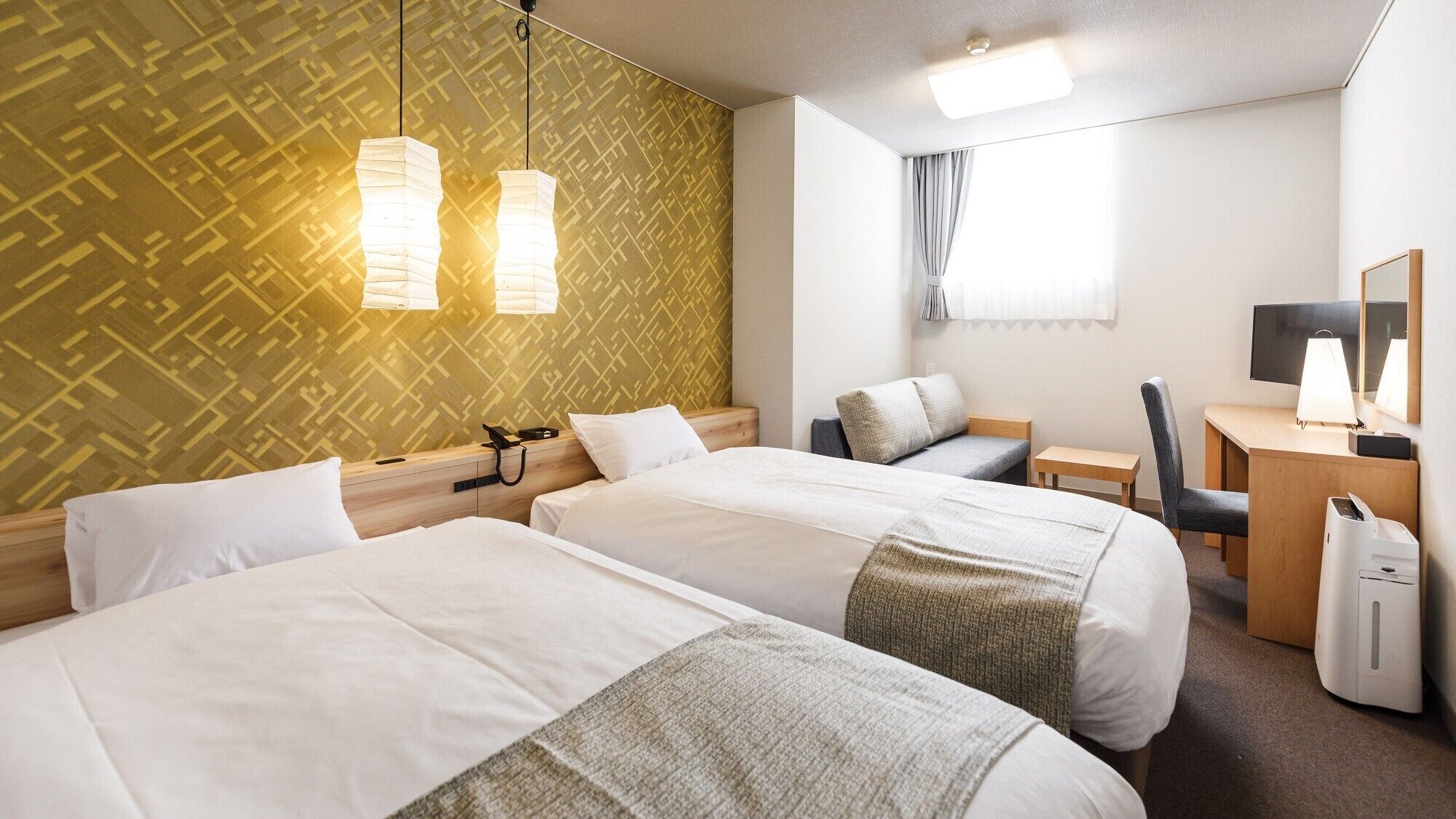 A hotel room with two beds, a desk, a chair, a desk lamp, a mirror, and a printer.