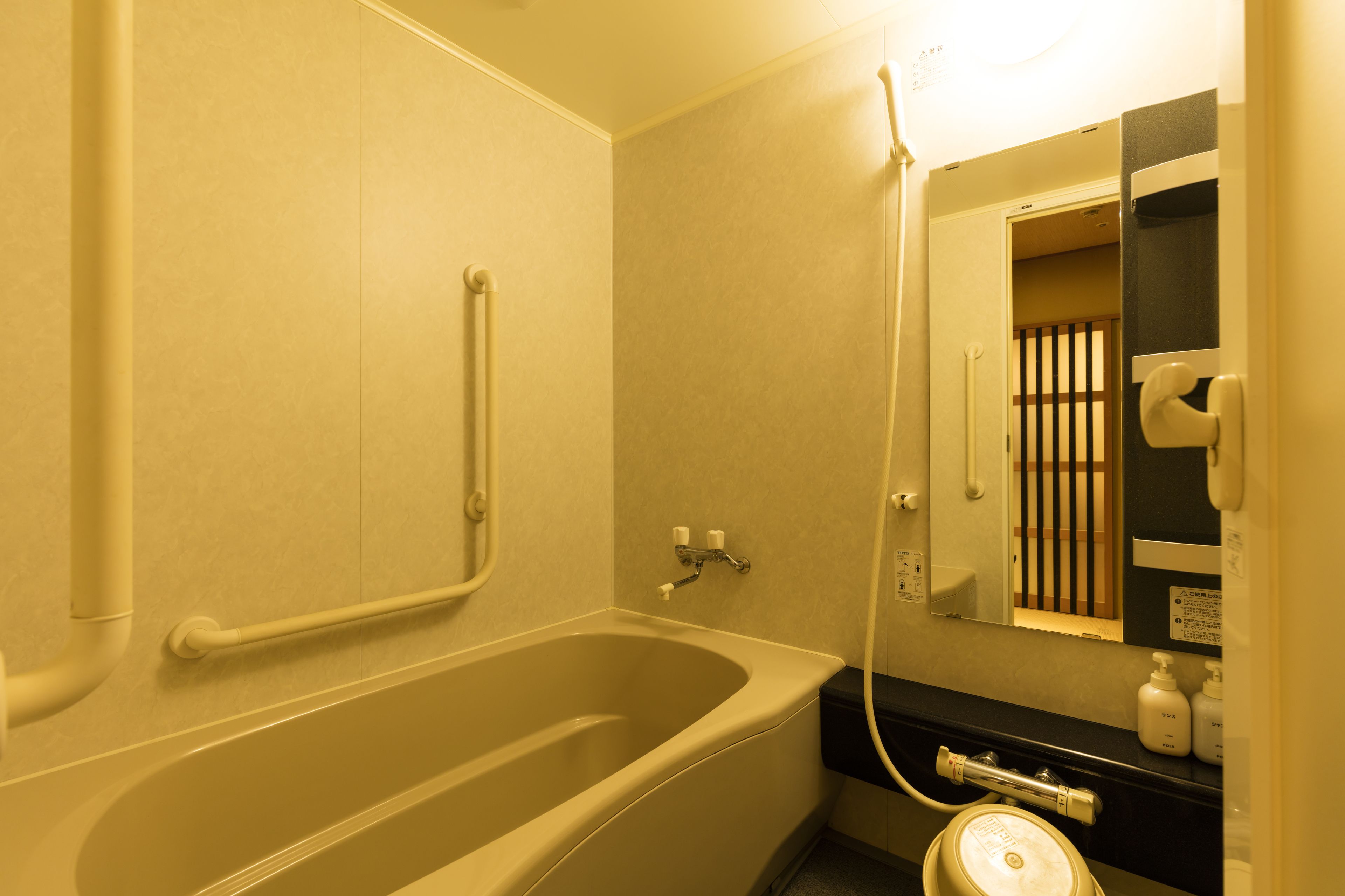 Un baño con bañera, barandilla, lavabo y espejo.