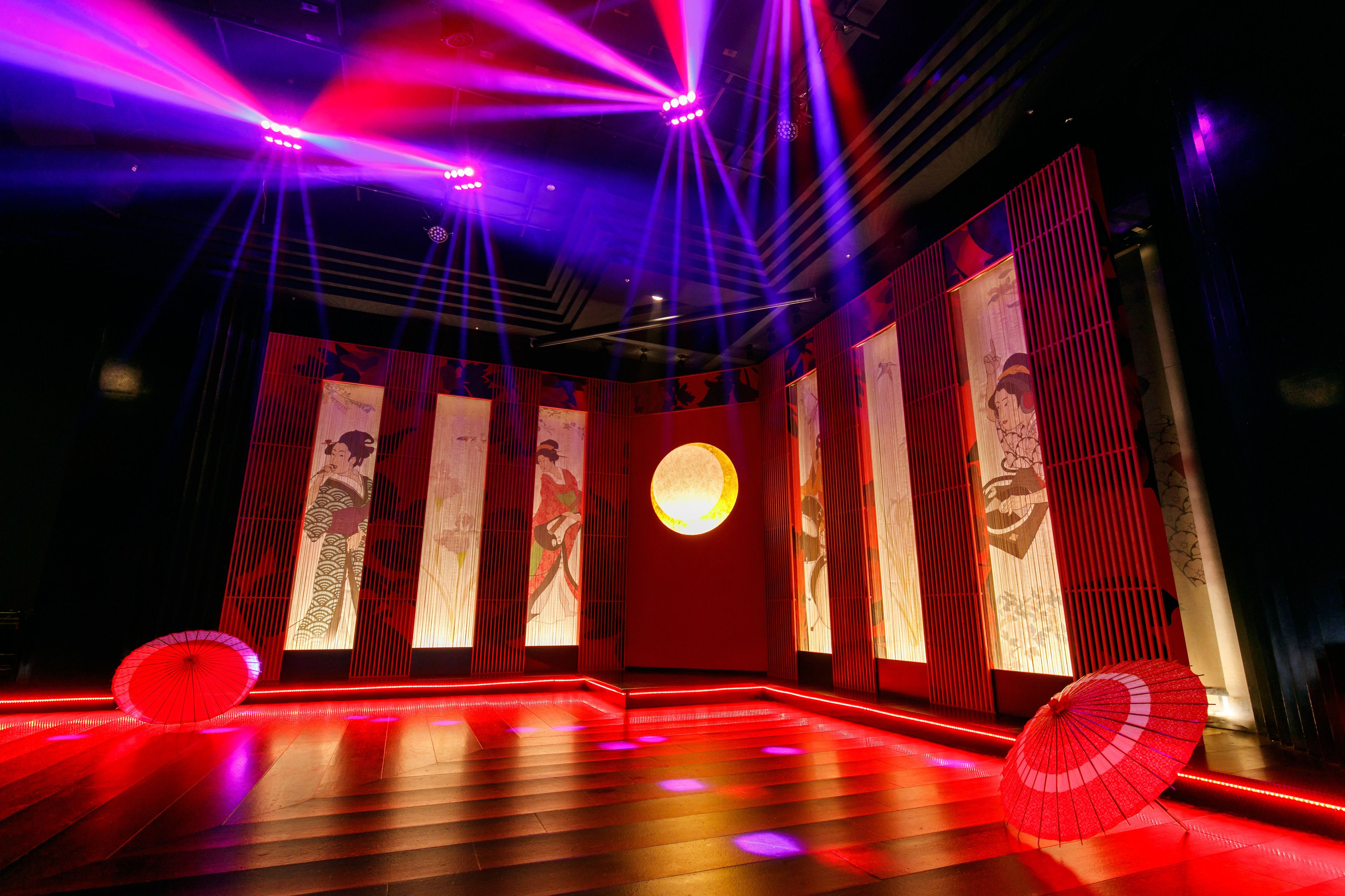 A stage with red lighting and traditional Japanese artwork.