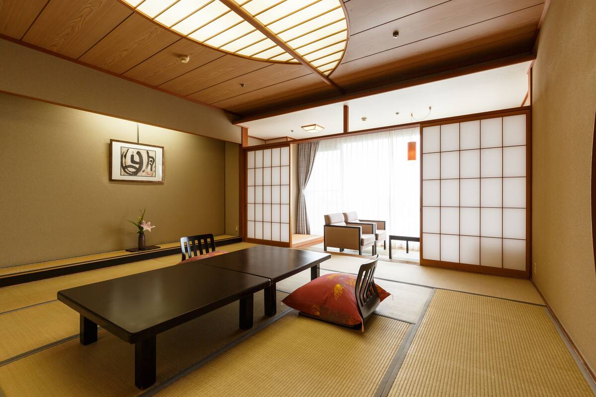 Ett traditionellt japanskt rum med tatamimattor på golvet, ett lågt bord och skjutdörrar.