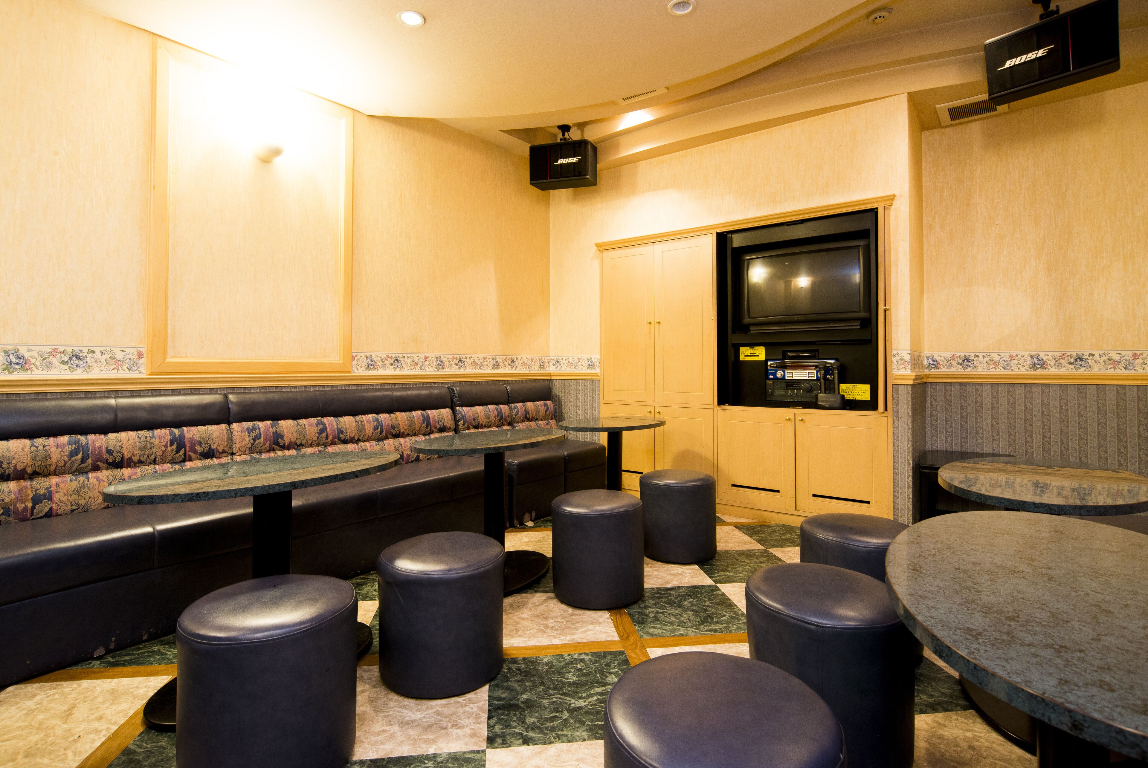 Un restaurante con área de asientos tipo cabina, mesas redondas y taburetes negros.