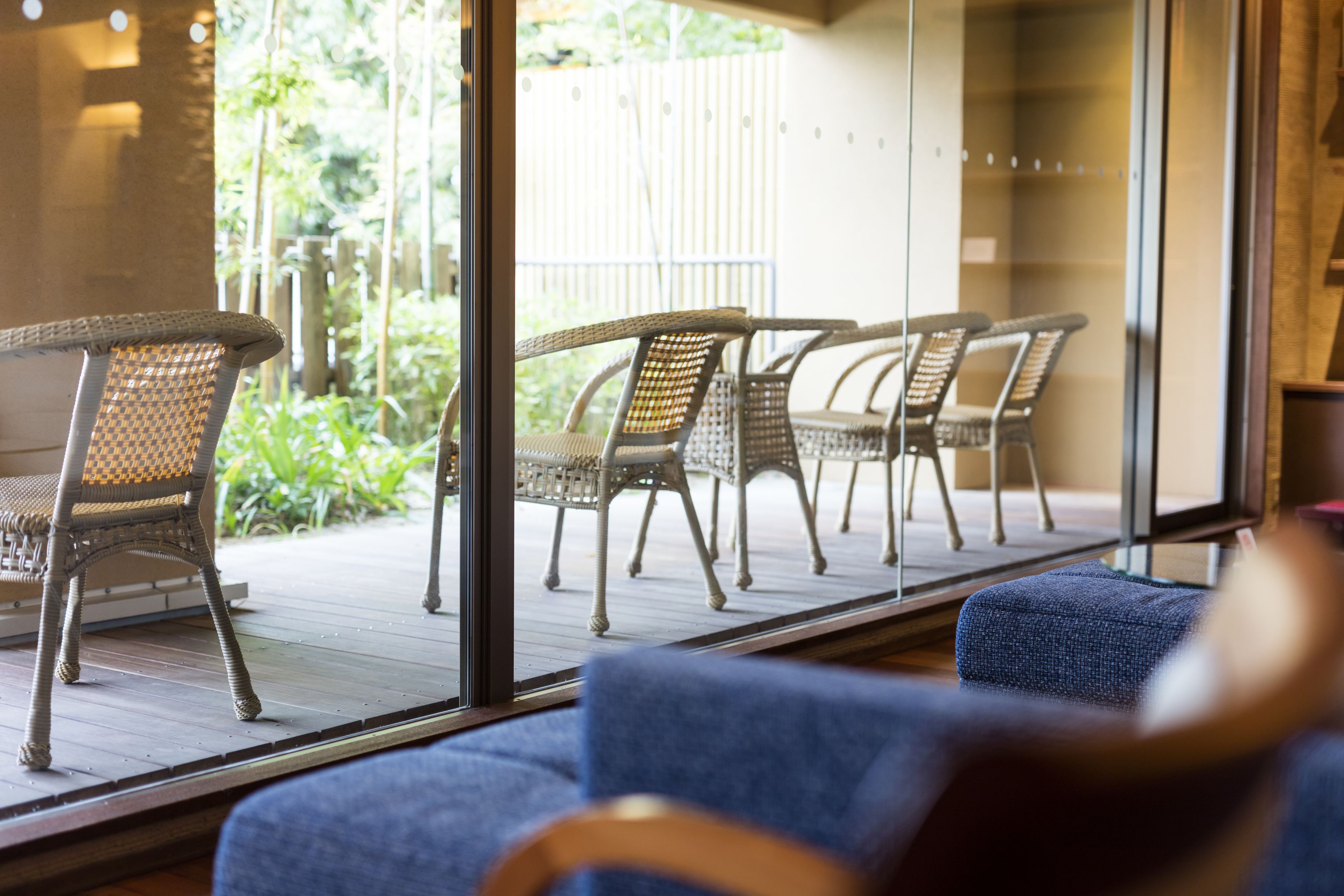 A room with a large glass door leading to an outdoor patio area with wicker furniture.