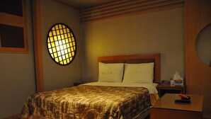 A hotel room with a bed, a bedside table with a phone and tissues, and a wall-mounted light fixture. - Motel Daeha (Seoul)