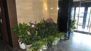 A lobby with a marble floor and potted plants arranged in a row. - Motel Daeha (Seoul)