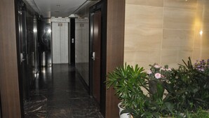 A modern hotel lobby with a marble floor, a wooden reception desk, and a potted plant with flowers. - Motel Daeha (Seoul)
