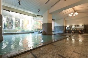 An indoor swimming pool with clear water, stone pillars, and a tiled floor.