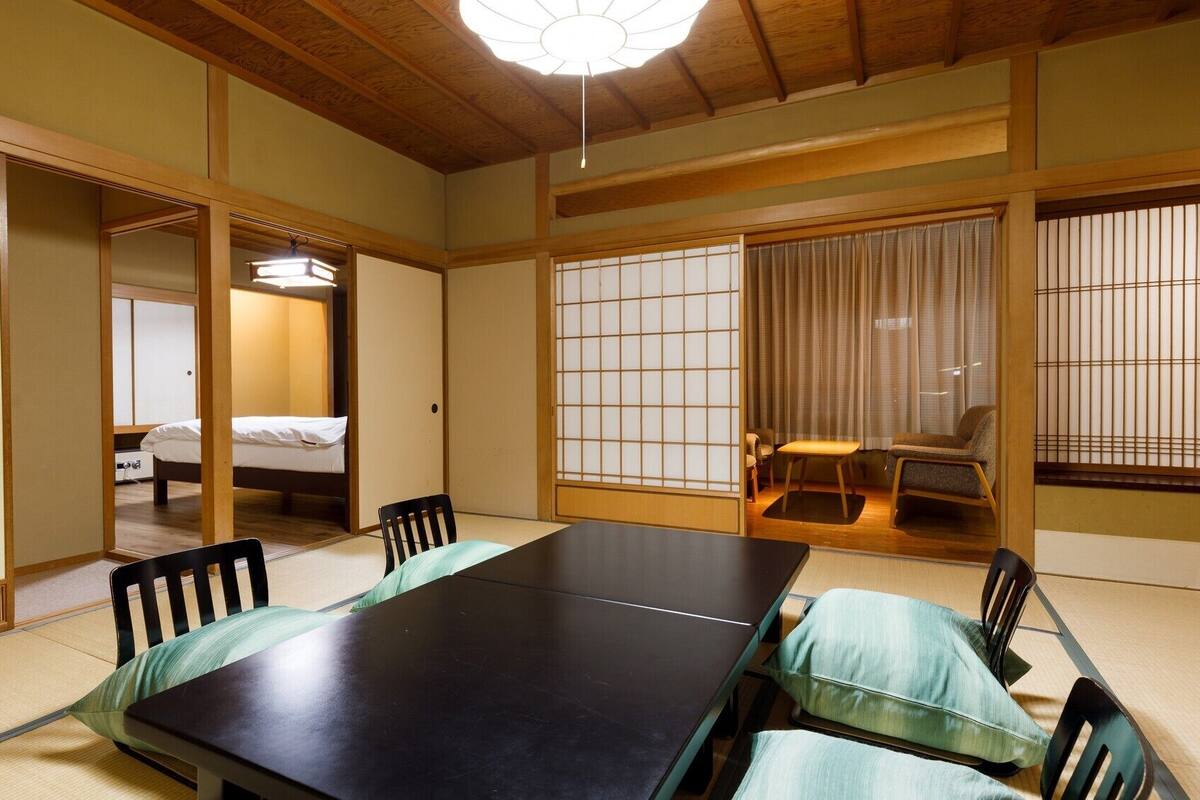 Una habitación japonesa tradicional con suelo de tatami, una mesa baja y puertas correderas shoji.