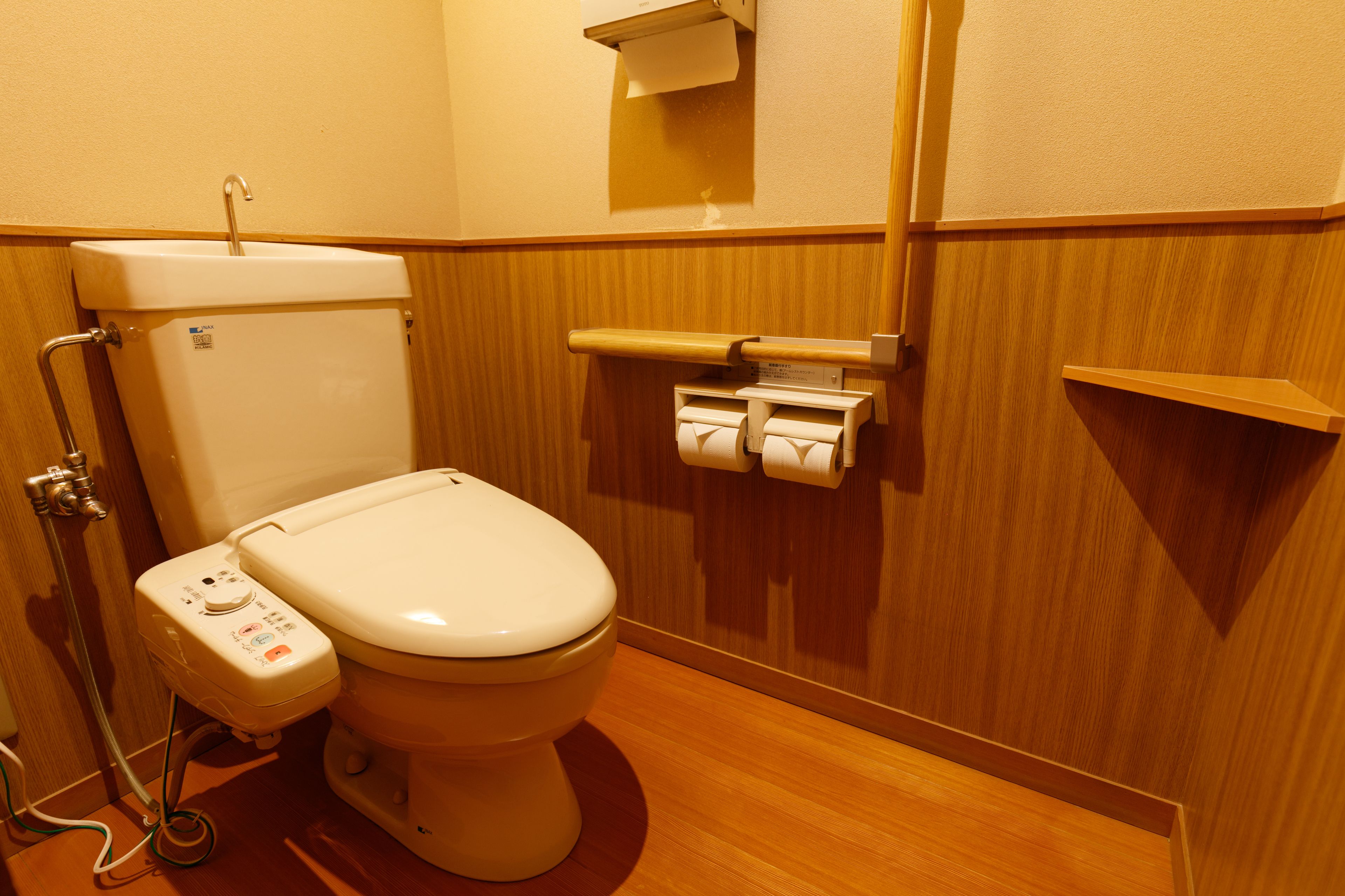 A modern bathroom with a toilet, a paper towel dispenser, and a soap dispenser.