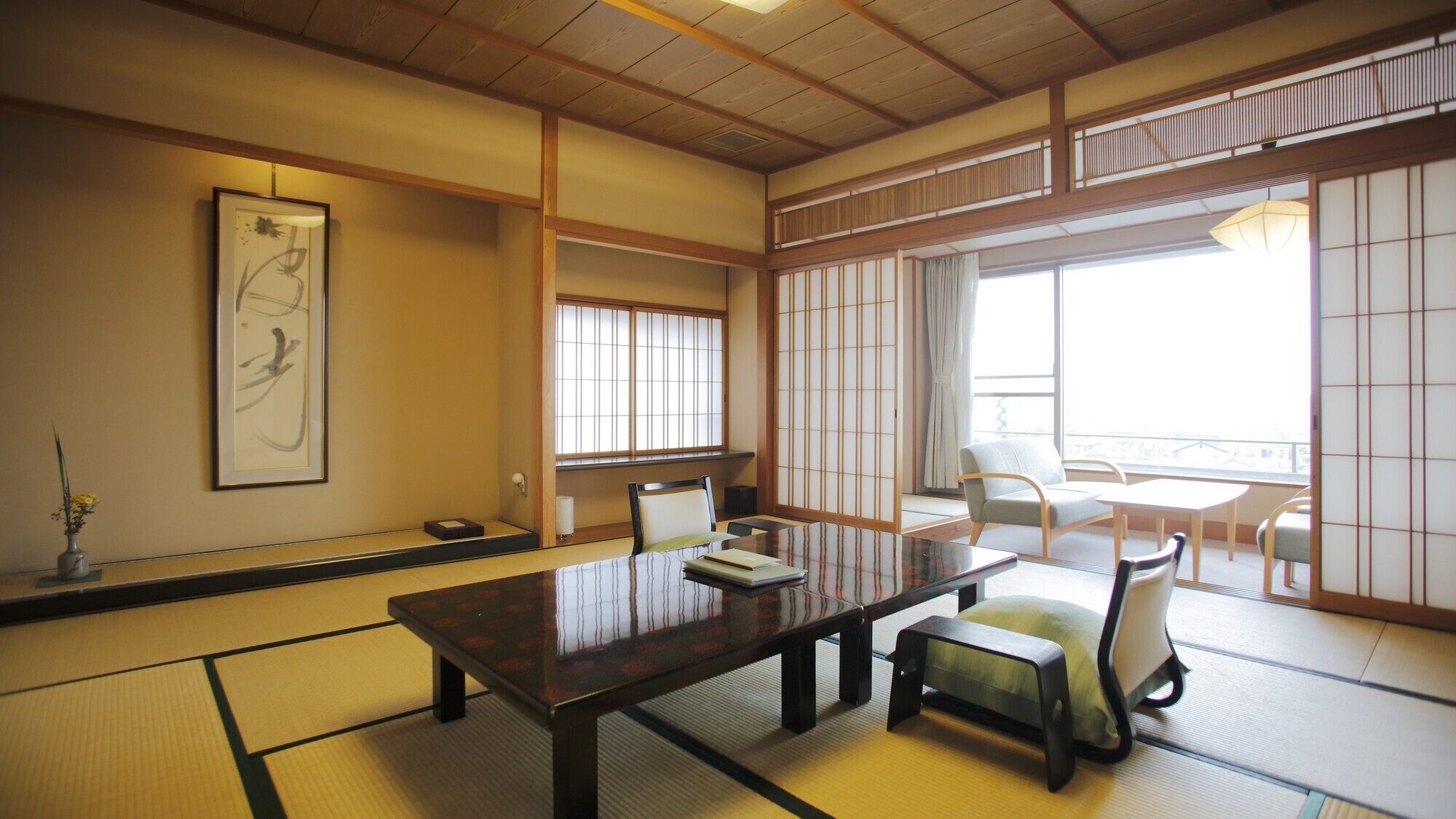 Una habitación japonesa tradicional con suelo de tatami, una mesa baja, sillas y puertas correderas shoji.