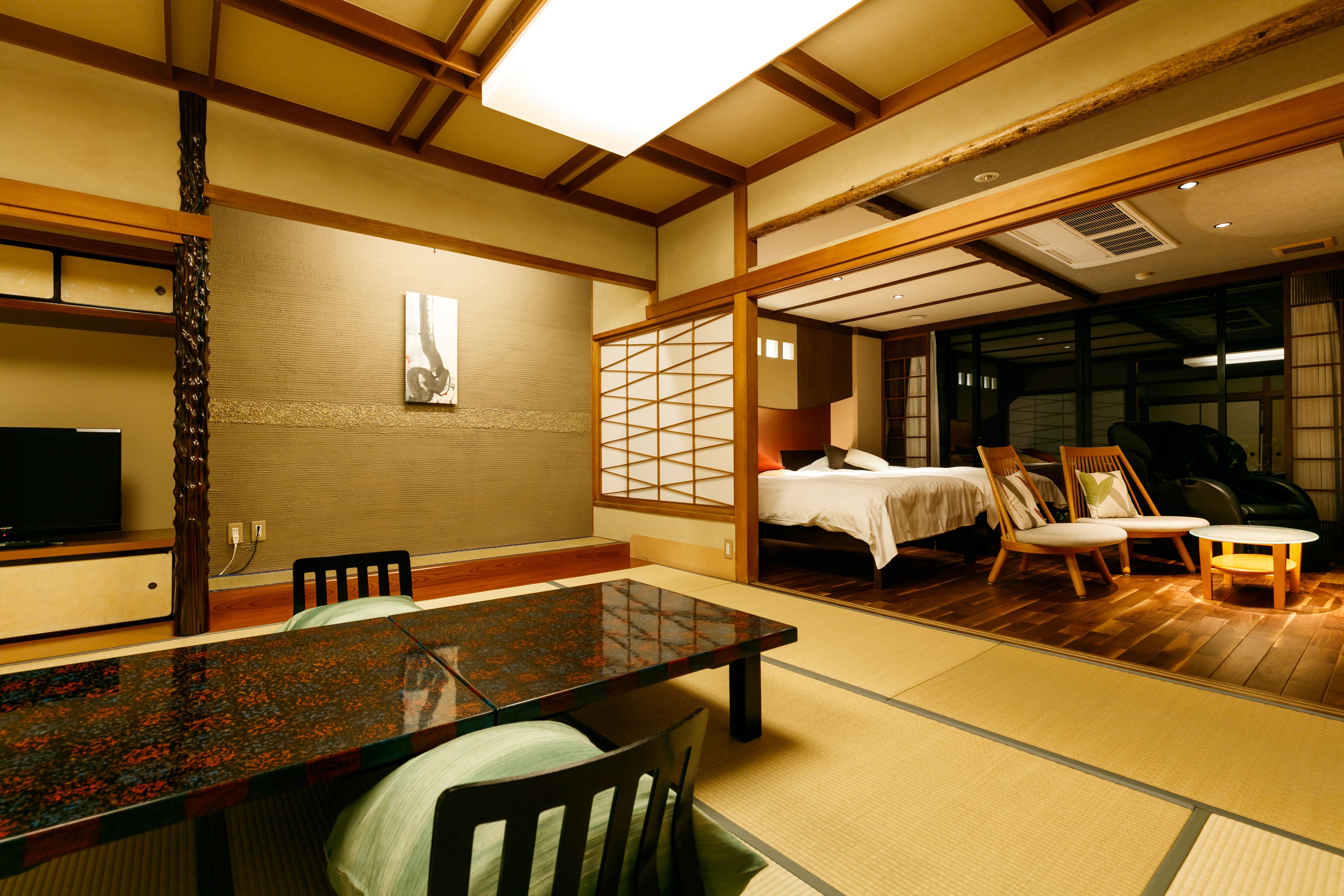Une pièce de style japonais traditionnel, avec un sol recouvert de tatamis, une table basse et un lit doté d’une tête de lit en bois.