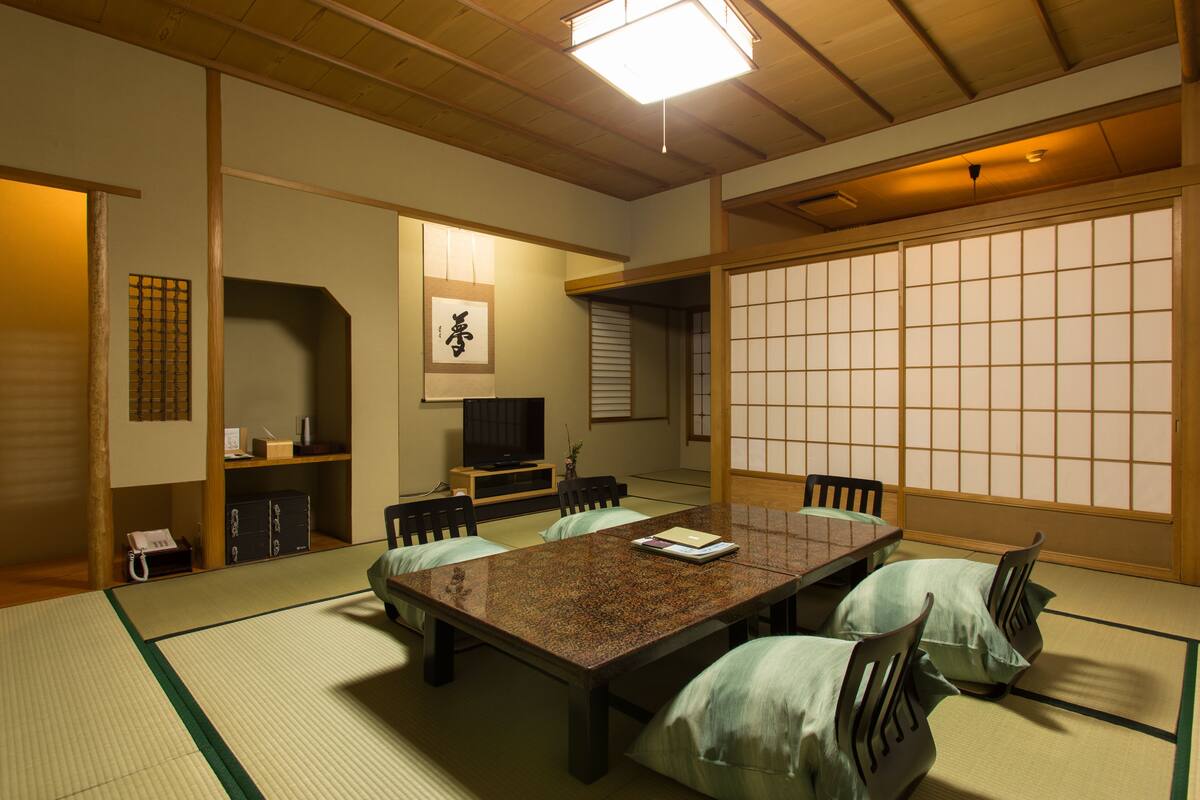 Una habitación japonesa tradicional con suelo de tatami, una mesa baja y paneles shoji.