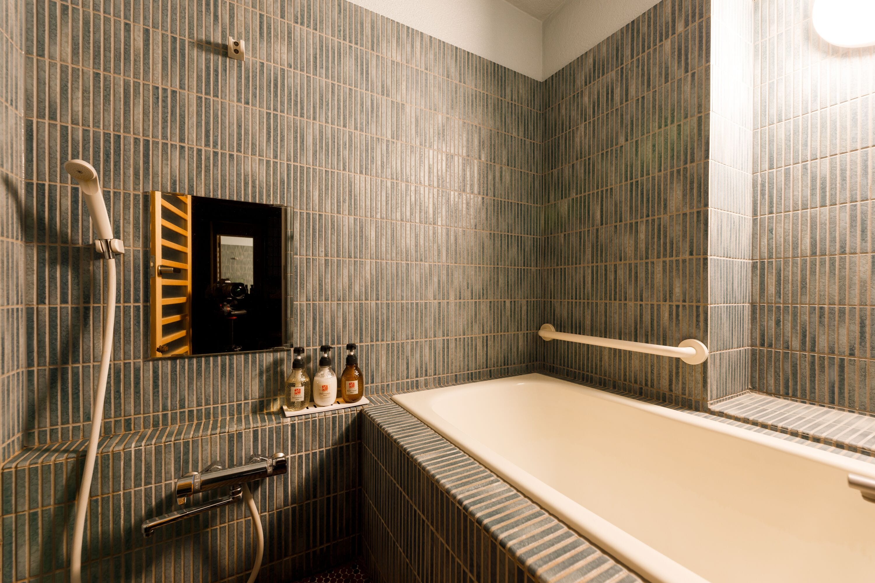 A bathroom with a bathtub, a towel rack, a mirror, and a shelf with toiletries.