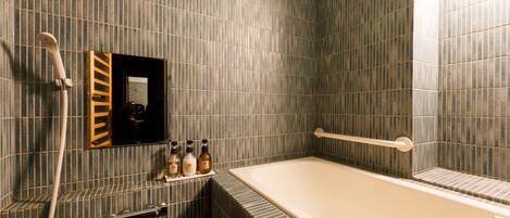 A bathroom with a bathtub, a towel rack, a mirror, and a shelf with toiletries.