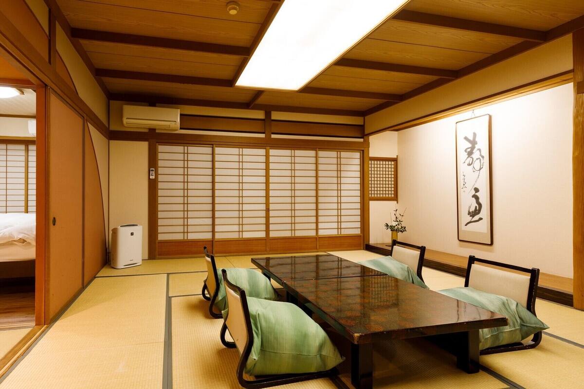 Una habitación japonesa tradicional con suelo de tatami, una mesa baja y puertas correderas shoji.