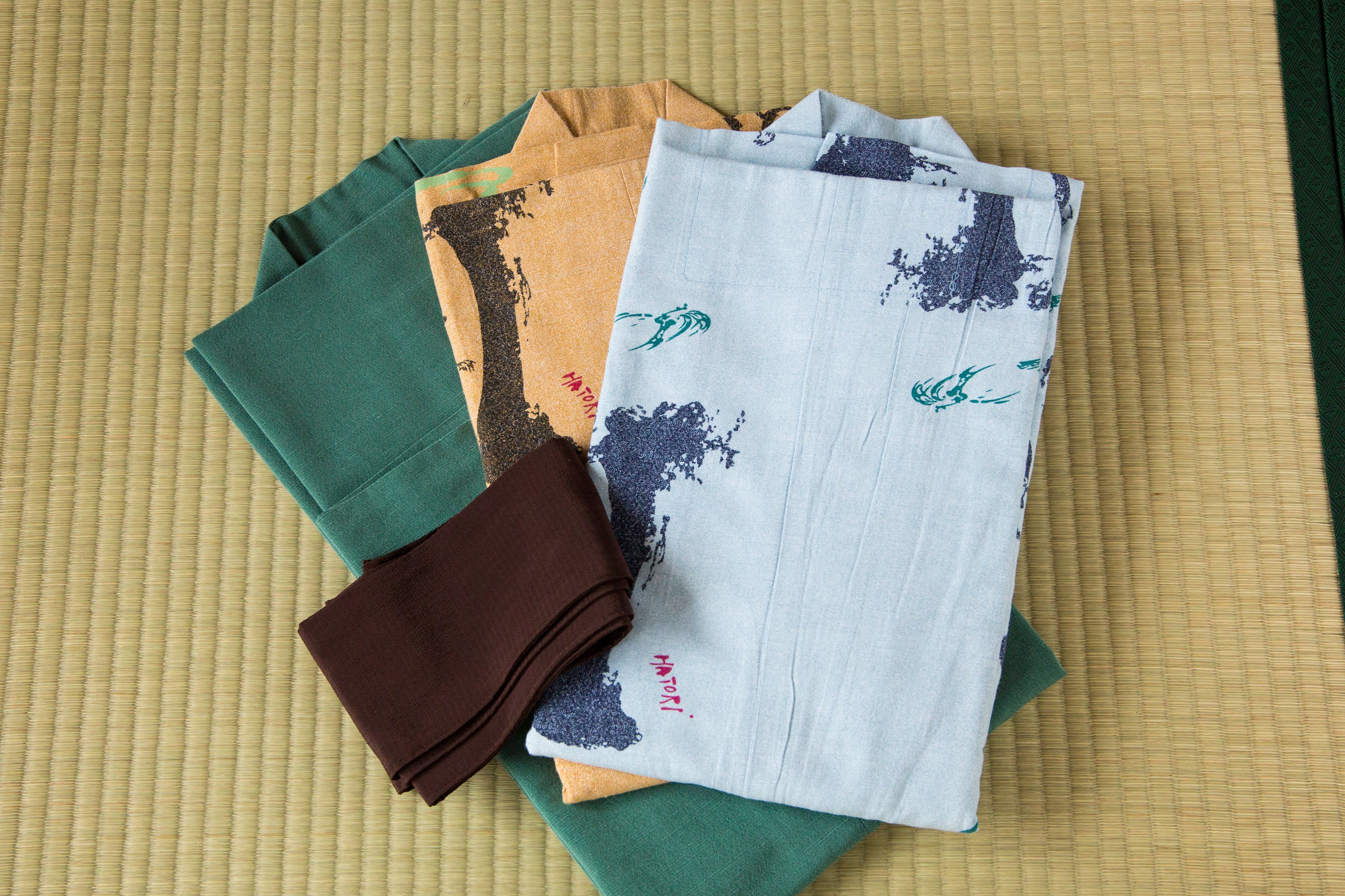 A set of folded towels in various colors on a textured surface.