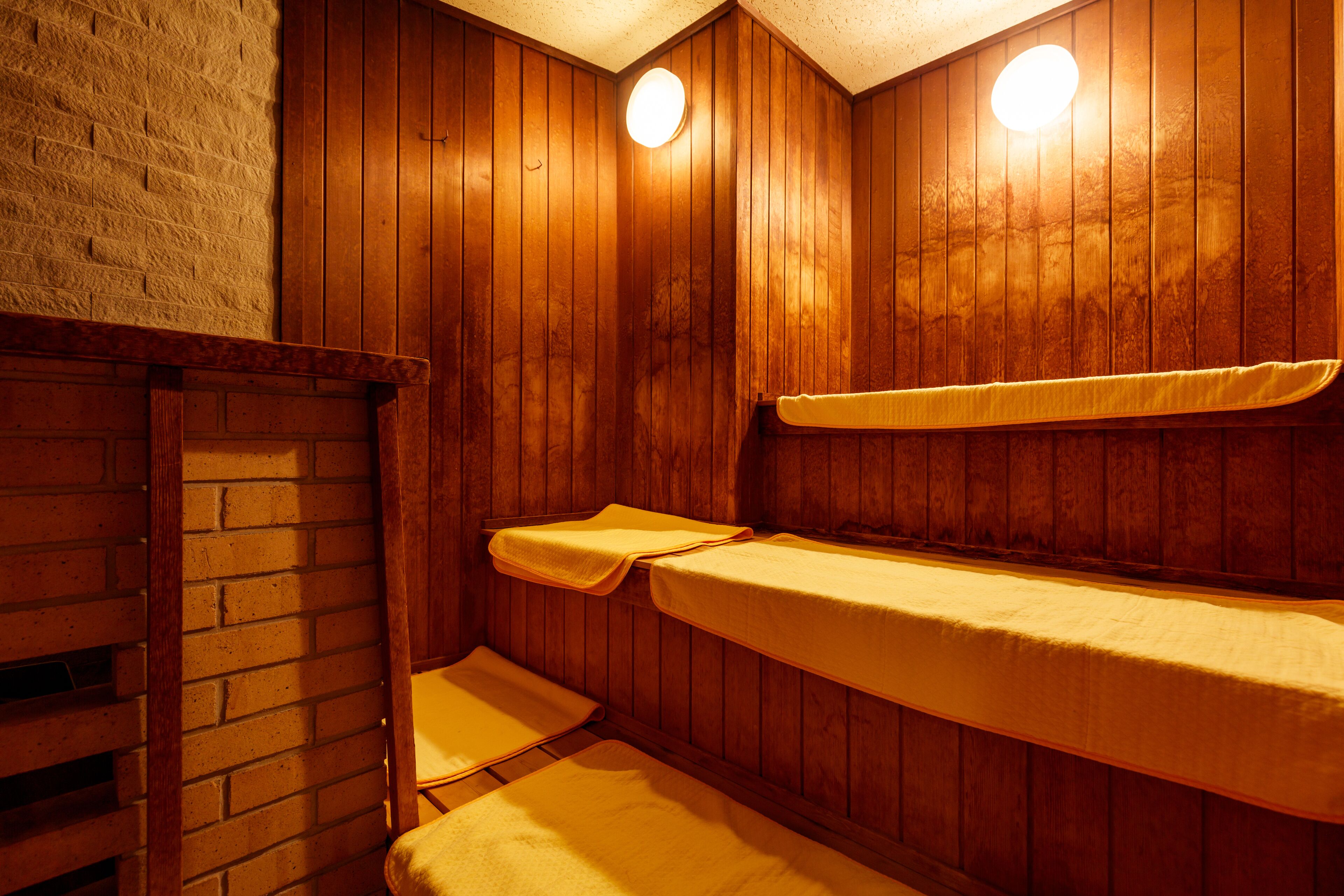 A wooden sauna with benches and a brick wall.