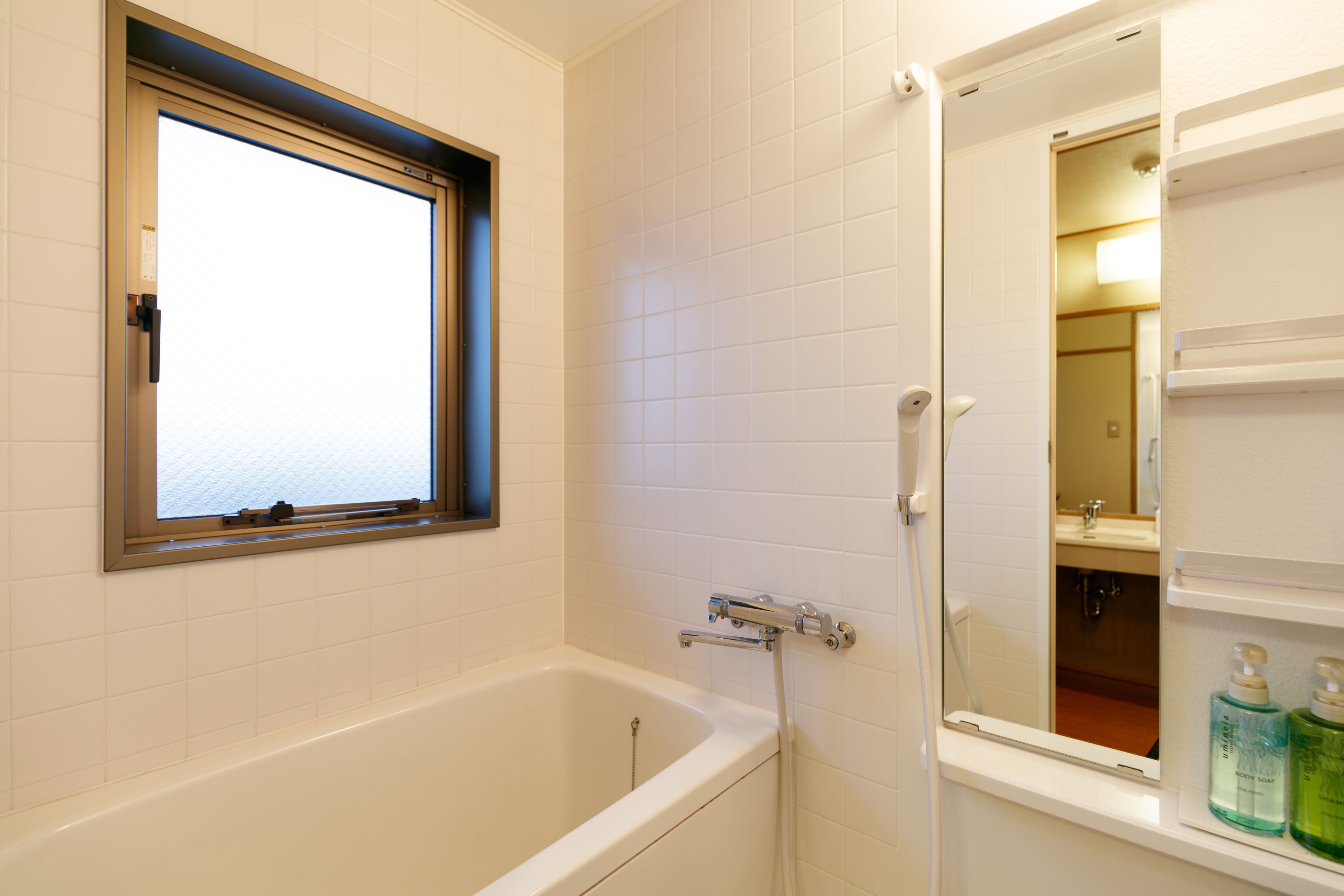 Un baño con una bañera, una ventana y un espejo.
