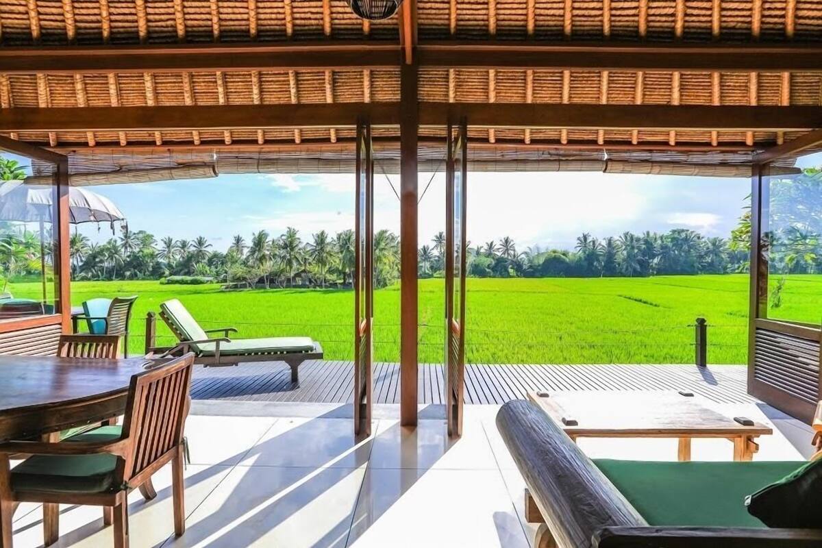 A covered outdoor seating area with a view of a green field.