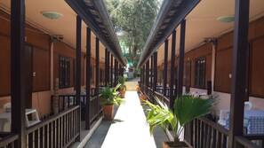 A covered corridor with wooden pillars, potted plants, and tables with checkered tablecloths. - Lucky Home Resort (Koh Samui)