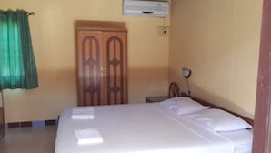 A hotel room with a bed, a wardrobe, an air conditioning unit, a nightstand, and a lamp. - Lucky Home Resort (Koh Samui)