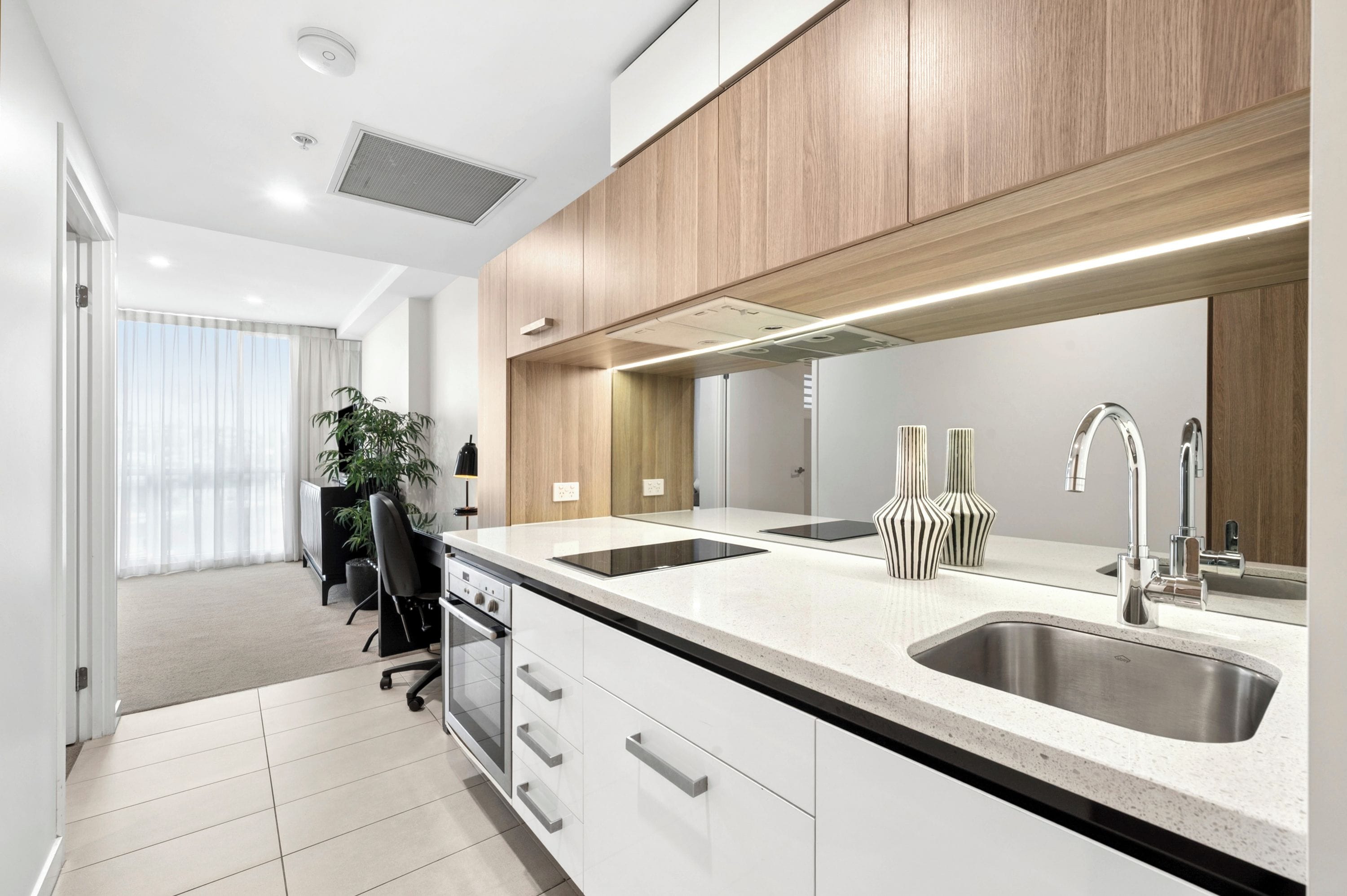 A modern kitchen with a double sink, stainless steel appliances, and a wooden accent wall.
