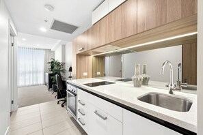 Una cocina moderna con un lavamanos doble, electrodomésticos de acero inoxidable y una pared de acento de madera.