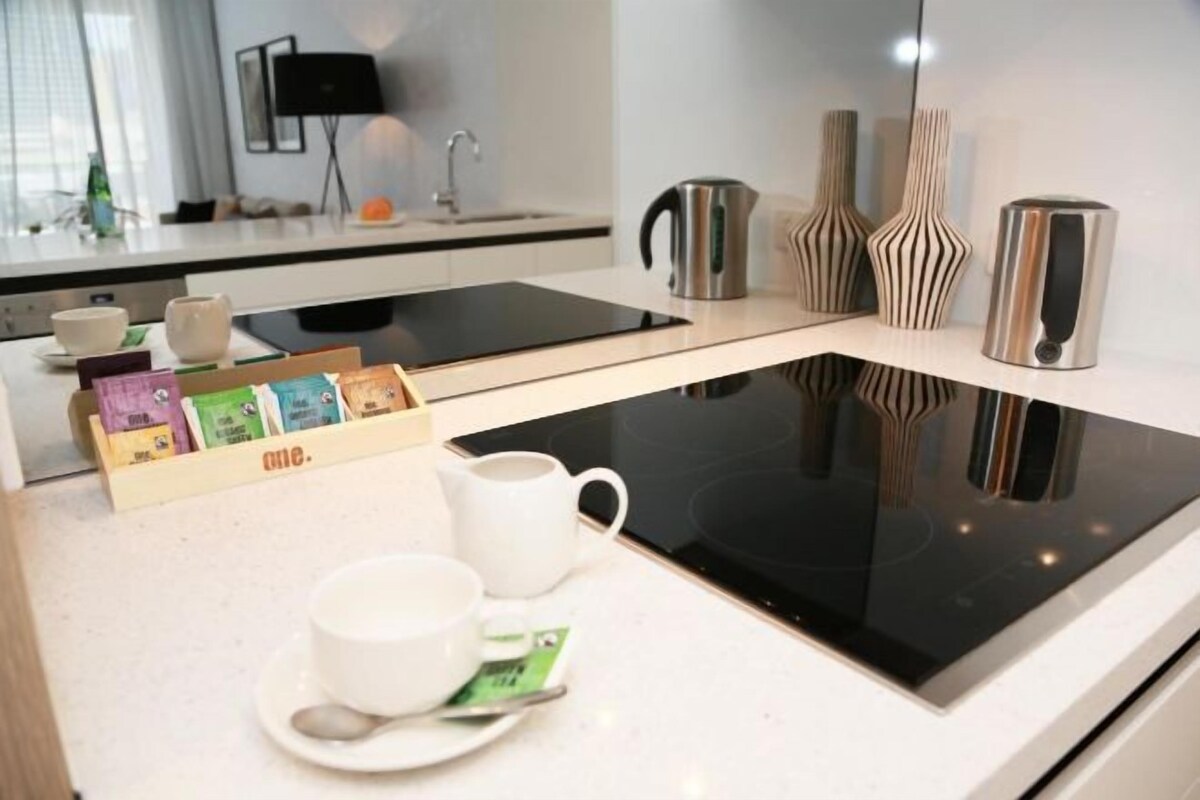 Una cocina moderna con tope de inducción negro, encimera blanca y cafetera.