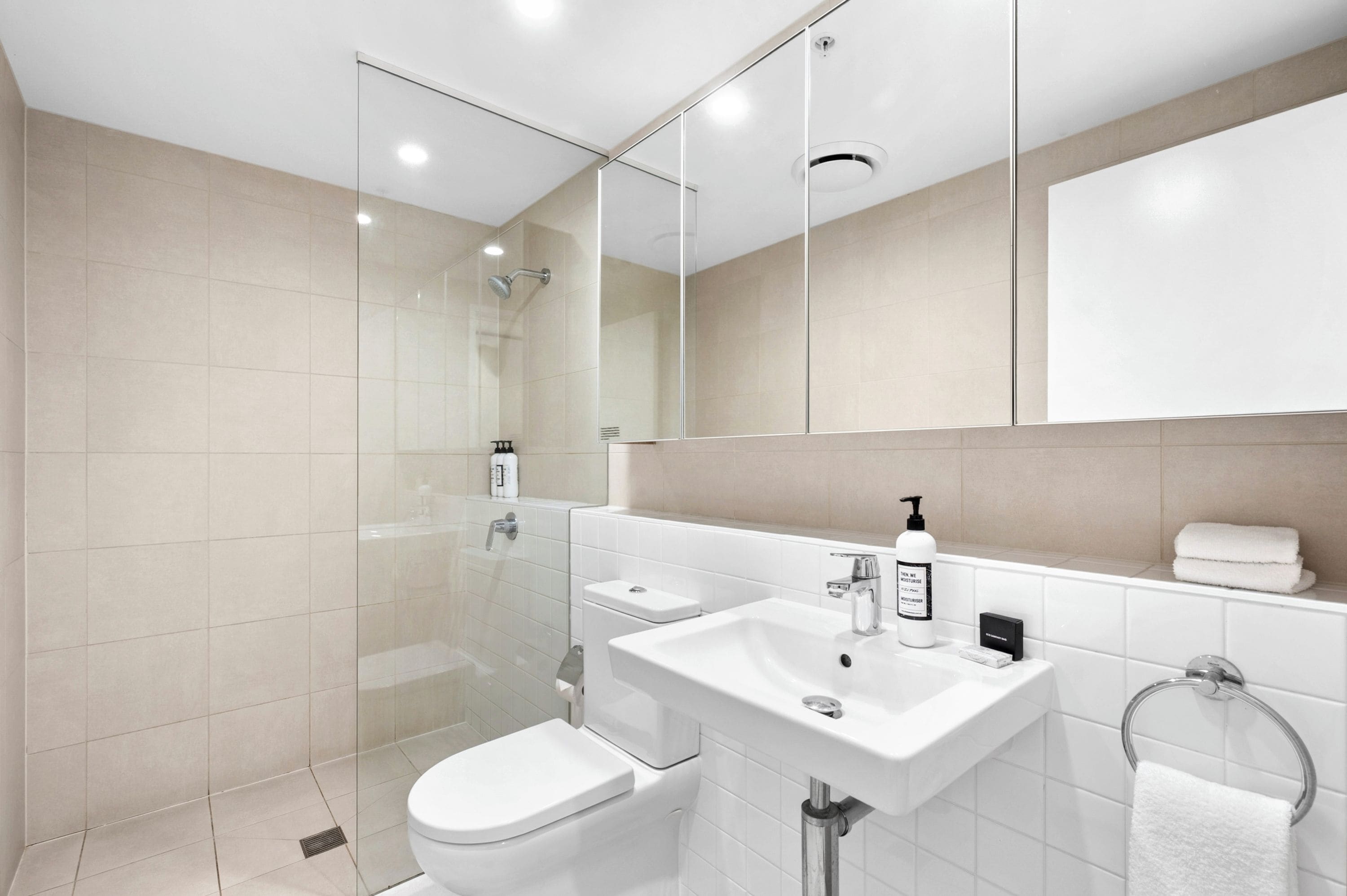 Une salle de bain moderne avec une douche à parois de verre, un lavabo blanc et des toilettes.