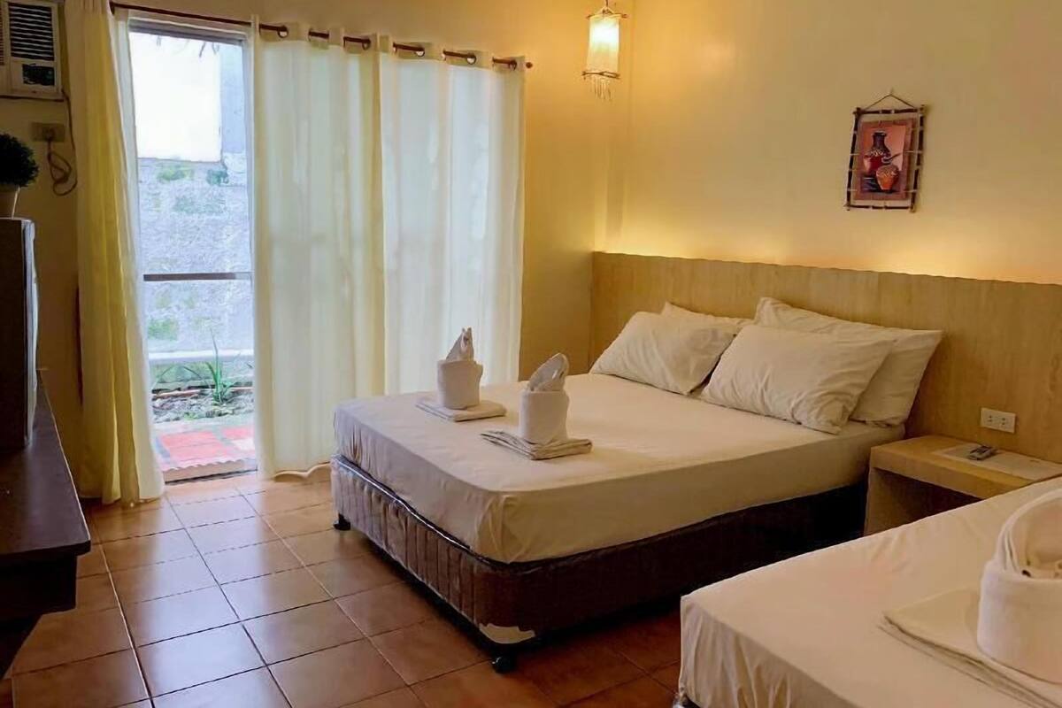 Une chambre d’hôtel avec un lit, une table de chevet et une vue par la fenêtre, qui est dotée de rideaux.