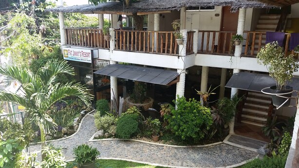 Un complexe hôtelier doté d’un espace extérieur couvert avec des sièges, d’une enseigne indiquant « Fat Jimmy’s Resort », et d’un chemin de pierre menant à l’entrée.