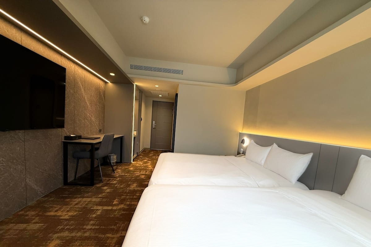 Habitación de hotel con dos camas, un escritorio y una silla.