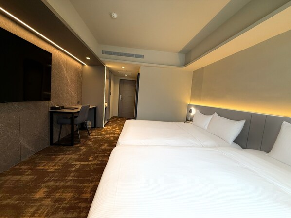 A hotel room with two beds, a desk, and a chair.