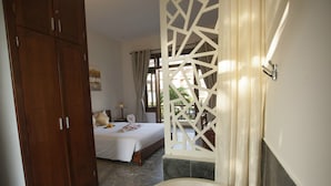 A bedroom with a large bed, a wooden wardrobe, and a bathroom with a bathtub. - Hoi An TNT Villa (Da Nang)