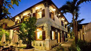 A two-story house with a balcony, potted plants, and outdoor seating. - Hoi An TNT Villa (Da Nang)