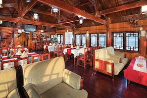 Enjoy dining with a view of the sea from this elegant dining area, featuring a high ceiling, ornate fan, and modern amenities.