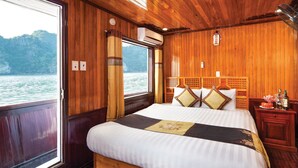 A wooden cabin room with a bed, a nightstand, and a window overlooking a body of water. - Halong Seasun Cruise (Bai Chay)