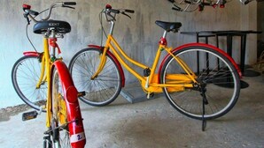 Een fietsenopslagruimte met meerdere fietsen, waaronder een gele met een rode frame.