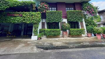 Un edificio con el letrero de Travelbee Heritage Inn en Dapitan, que presenta un estilo arquitectónico tradicional, con plantas y flores.