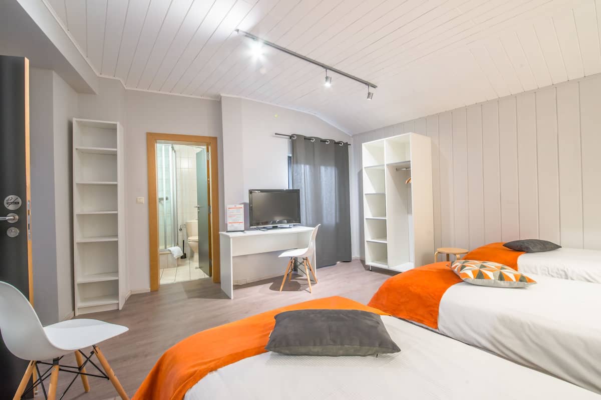 A modern hotel room with a bed, a desk, and a wardrobe.