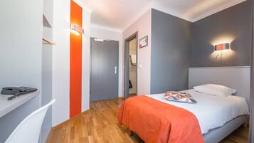 A modern hotel room with a bed, a desk, and a chair.