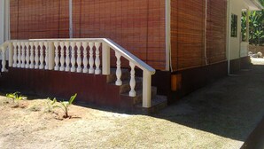 Ein Gebäude mit Holzfassade, weißem Geländer und einem kleinen Garten mit Pflanzen.