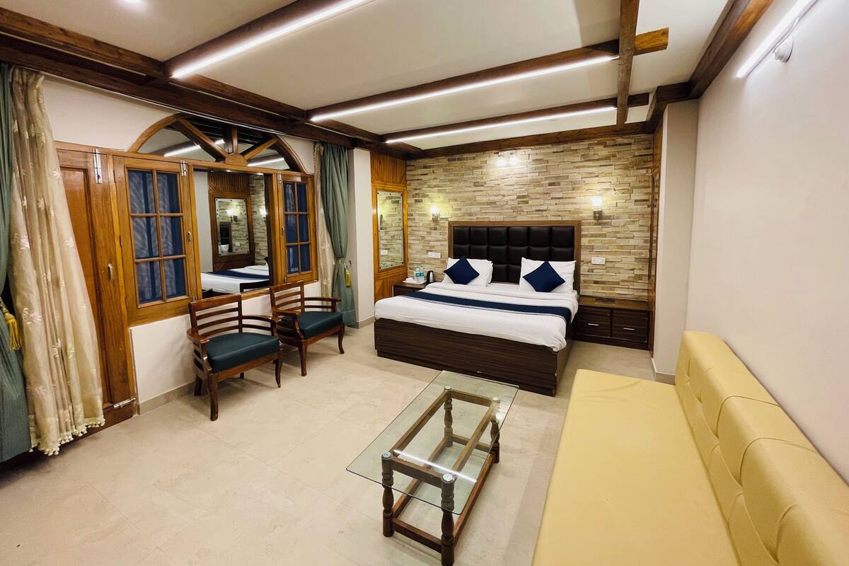 A bedroom with a bed, a chair, a small table, and a sofa.