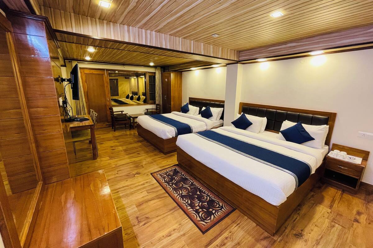 A hotel room with two beds, a desk, and a mirror.