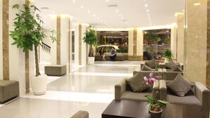 A spacious lobby with a reception desk, seating area, and potted plants. - International Hotel (Can Tho)