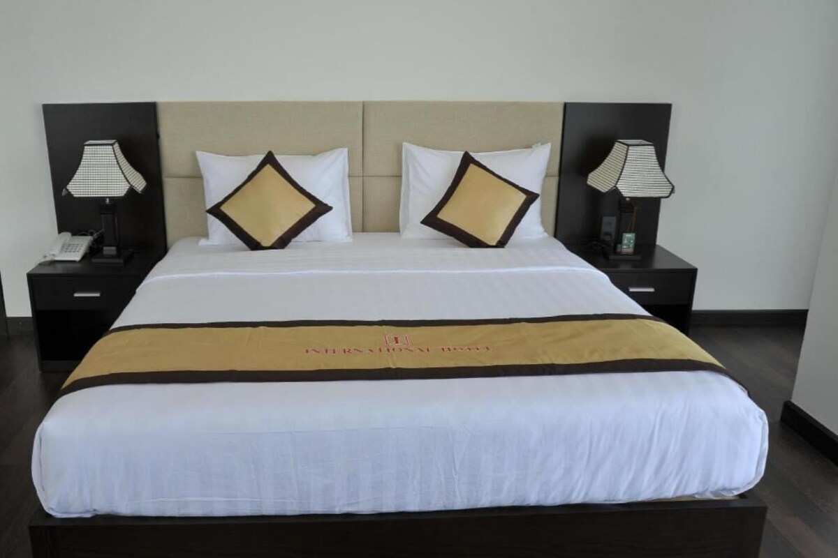 A hotel room with a large bed, two bedside tables with lamps, and a headboard.