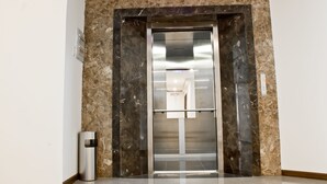 An elevator with a marble wall and a metallic finish. - International Hotel (Can Tho)