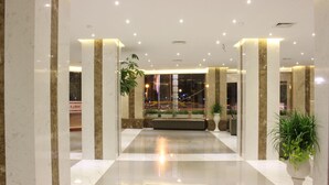 A spacious lobby with marble columns, a seating area, and potted plants. - International Hotel (Can Tho)