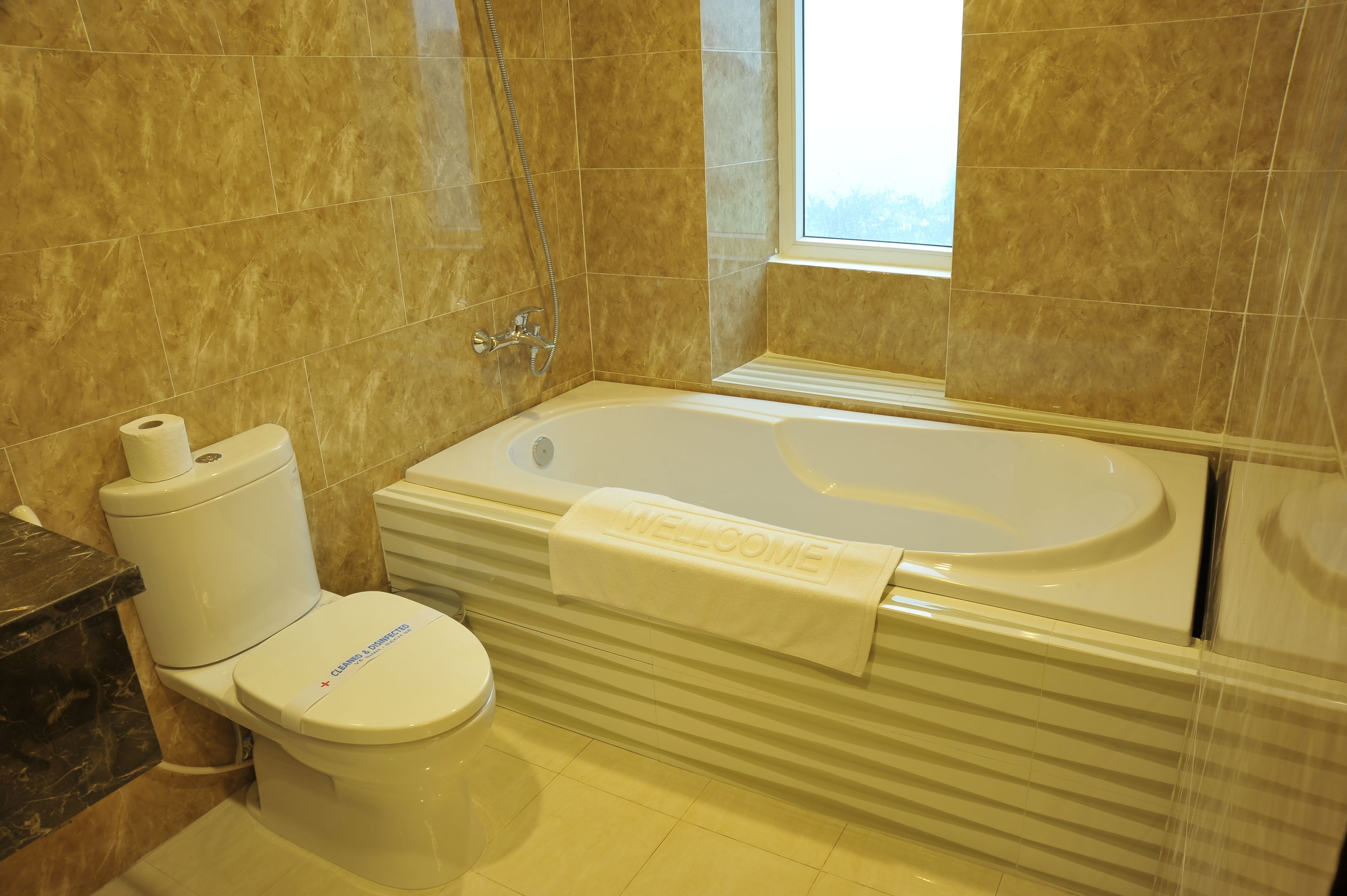A bathroom with a toilet, a bathtub, and a window.